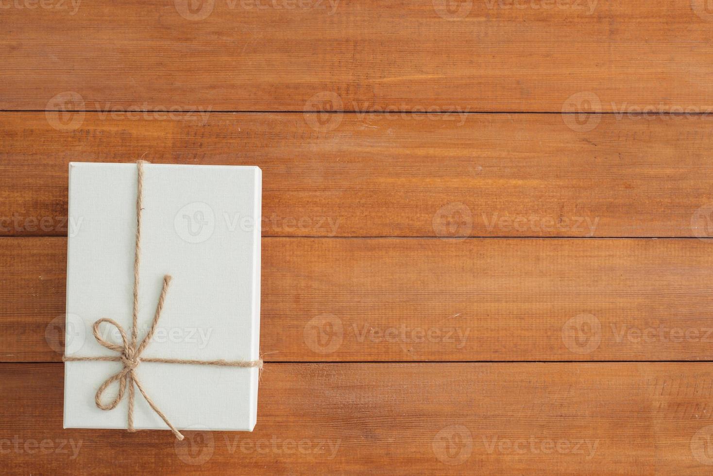 Christmas and New Year holidays gift box wrapped with white paper and ribbon bow on wood table - top view on wooden table top background. photo