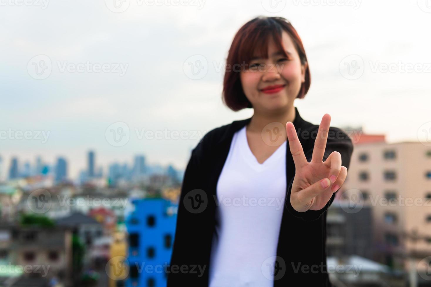 Alone asian woman sitting at rooftop of building see cityscape view in evening sunset time.lonely emotion photo