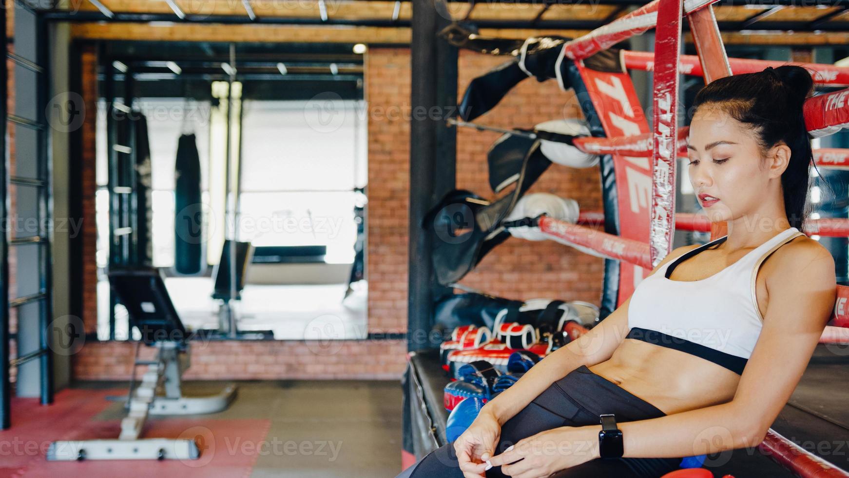 El entrenamiento del ejercicio de kickboxing de la señora joven de Asia se siente cansado después del entrenamiento deportivo en el ring de boxeo en la clase de gimnasia. deportista actividad recreativa, entrenamiento funcional, concepto de estilo de vida saludable. foto