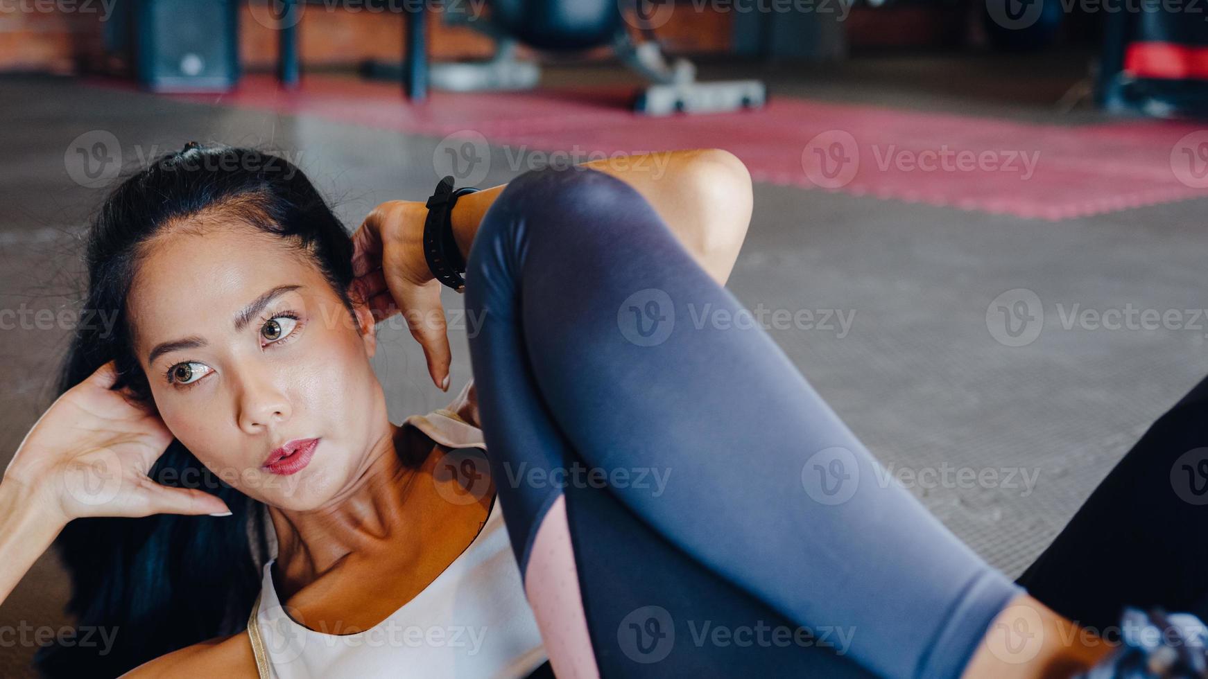 Hermosa joven asiática ejercicio haciendo ejercicio para quemar grasa en bicicleta crunch en clase de gimnasia. atleta con six pack, actividad recreativa deportista, entrenamiento funcional, concepto de estilo de vida saludable. foto