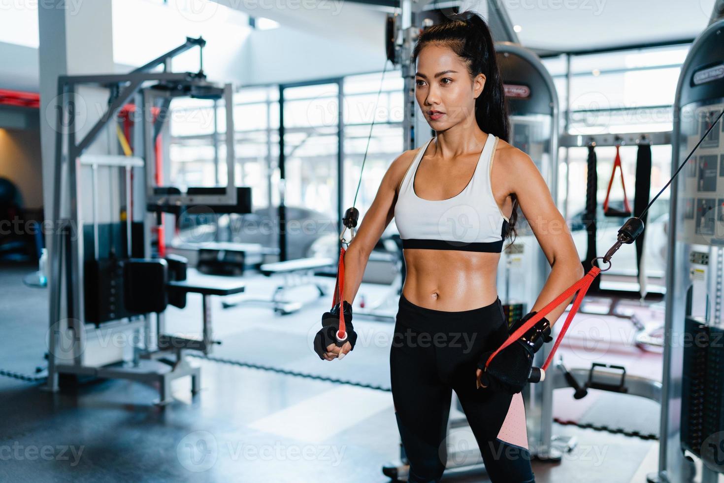 Asia joven dama ejercicio haciendo ejercicio-máquina de cable cruzado ejercicios para quemar grasa en la clase de gimnasia. atleta con six pack, actividad recreativa deportista, entrenamiento funcional, estilo de vida saludable. foto