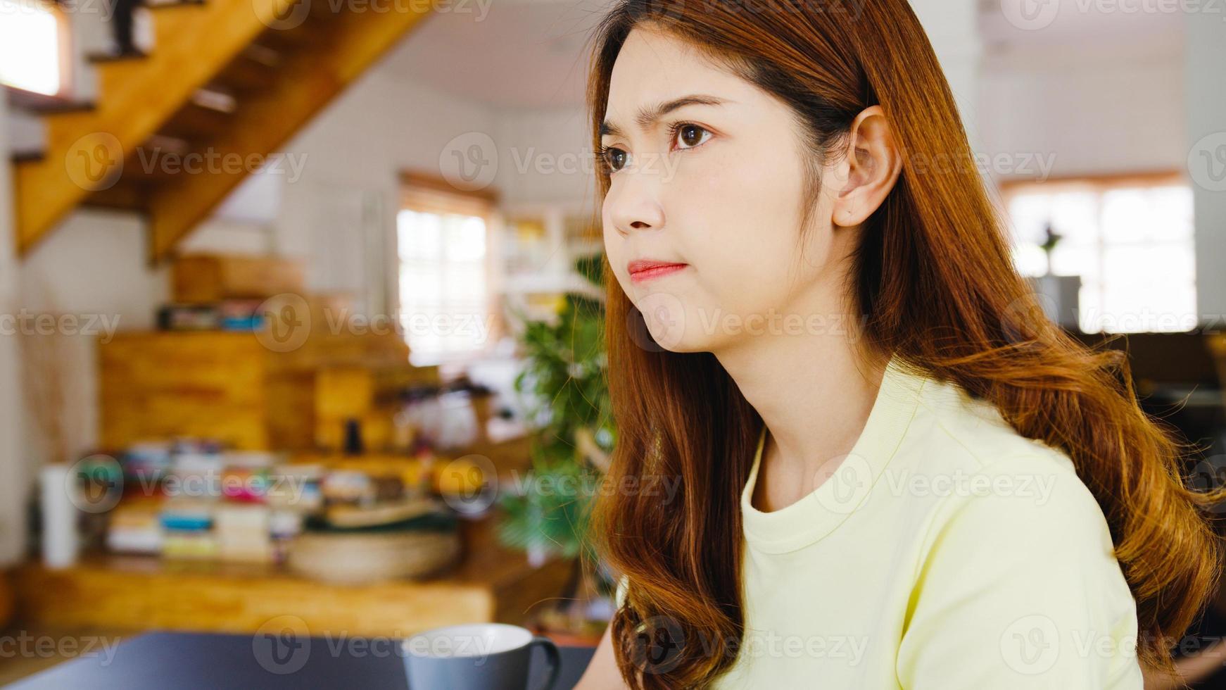 Retrato de ropa casual de mujeres asiáticas independientes usando una computadora portátil que trabaja en la sala de estar en casa. trabajo desde casa, trabajo a distancia, autoaislamiento, distanciamiento social, cuarentena para la prevención del coronavirus. foto