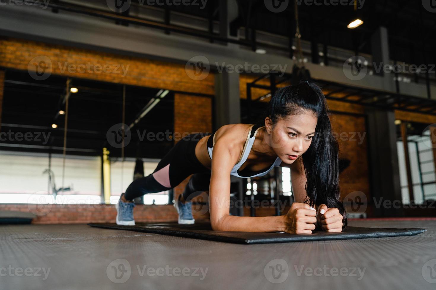 Happy young Asia lady exercise doing plank fat burning workout in fitness class. Athlete with six pack, Sportswoman recreational activity, functional training, healthy lifestyle concept. photo