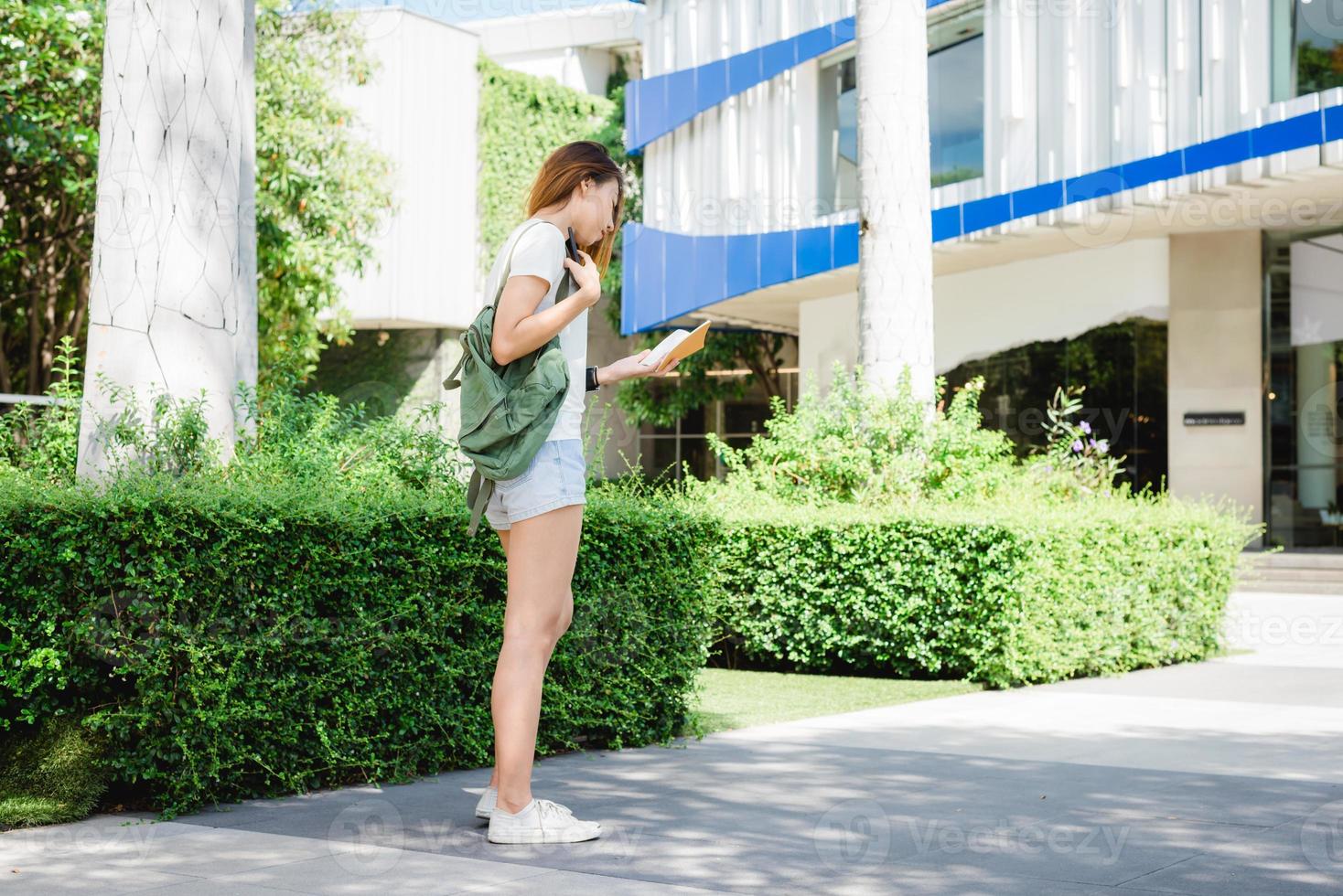 mochilero turista mujer asiática sonriendo y usando smartphone viajando solo vacaciones al aire libre en las calles de la ciudad de bangkok - tailandia. foto