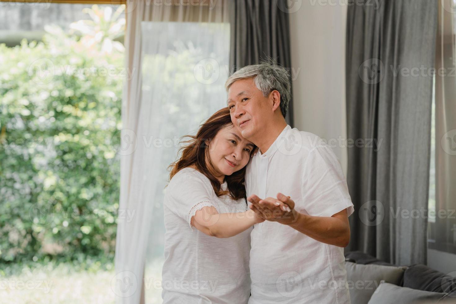 Asian elderly couple dancing together while listen to music in living room at home, sweet couple enjoy love moment while having fun when relaxed at home. Lifestyle senior family relax at home concept. photo