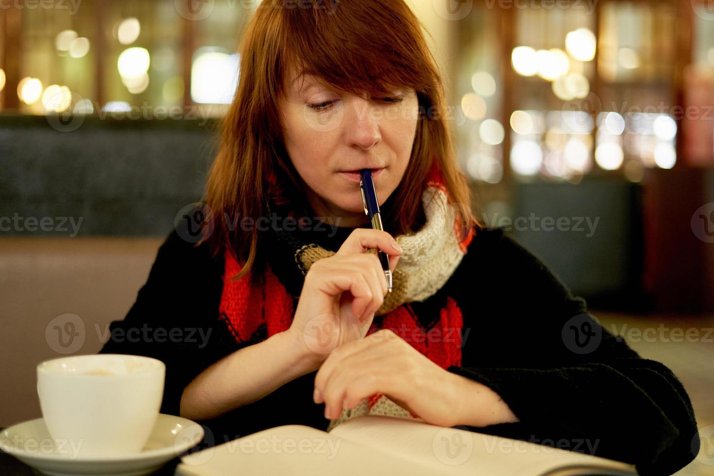 Woman in cafe writes in diary, bullet journal. Slow life, social detox, freelance, planning photo