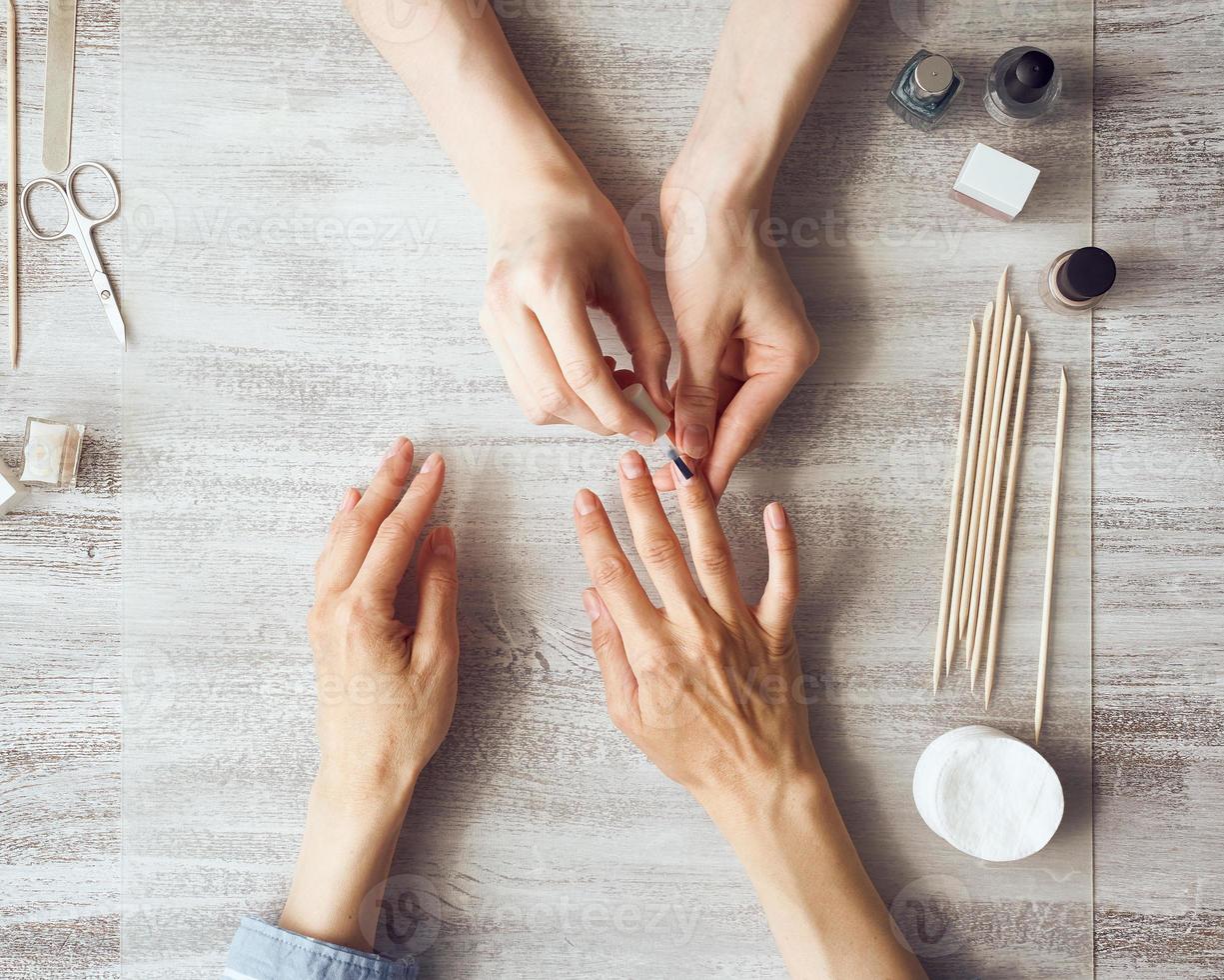 Mother and daughter do manicure, paint nails with varnish. Home self-care during quarantine photo