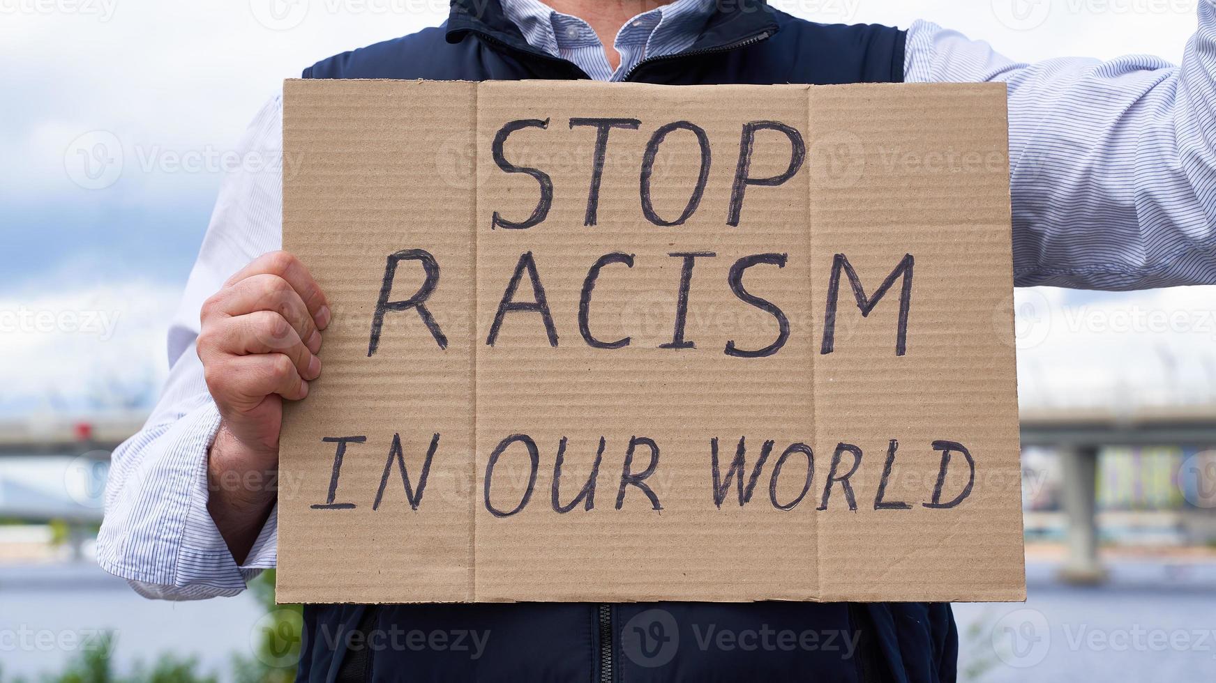 Stop racism concept. Unrecognizable white person holds sign with text against racist. photo