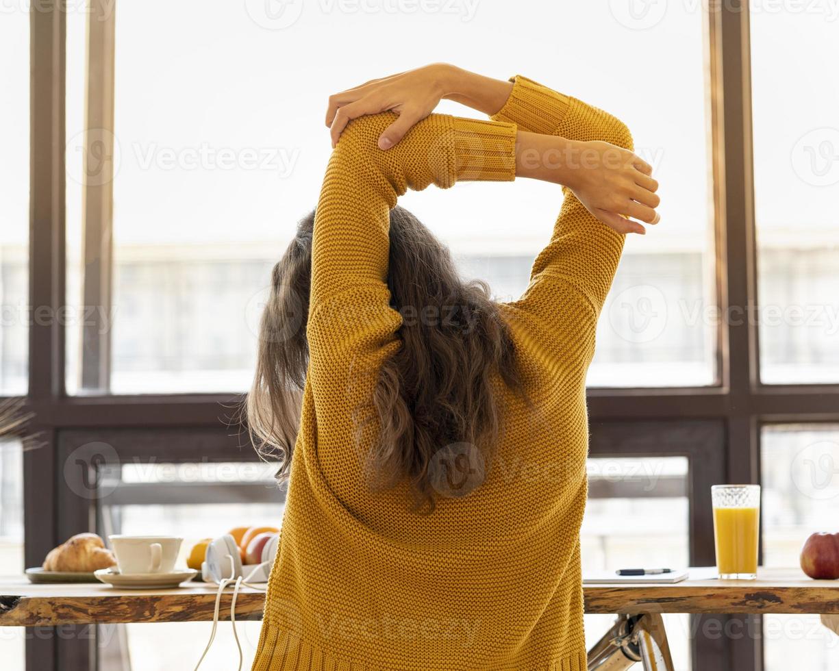 Vista posterior de una mujer joven sin rostro con rigidez muscular, tensión y dolor en las articulaciones foto