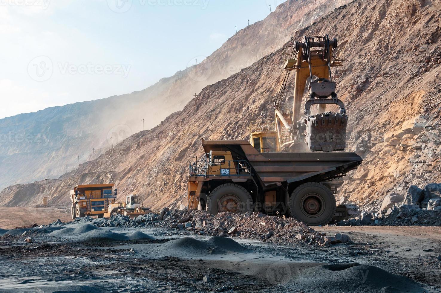 Los camiones volquete de mina a cielo abierto conducen solo zona industrial de la cantera de mineral de hierro foto