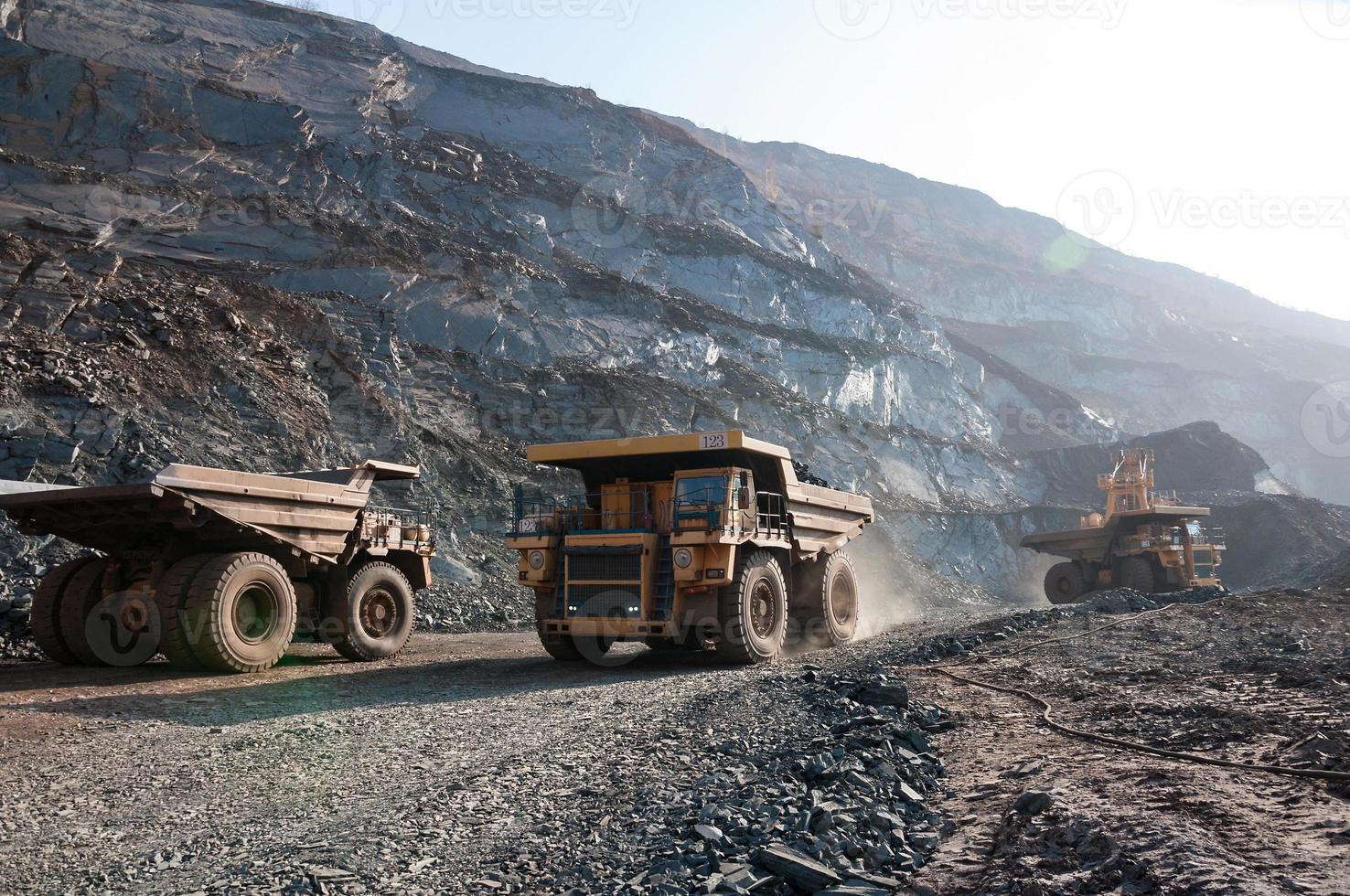 open cast mine dump trucks drive alone industrial area of iron ore quarry photo