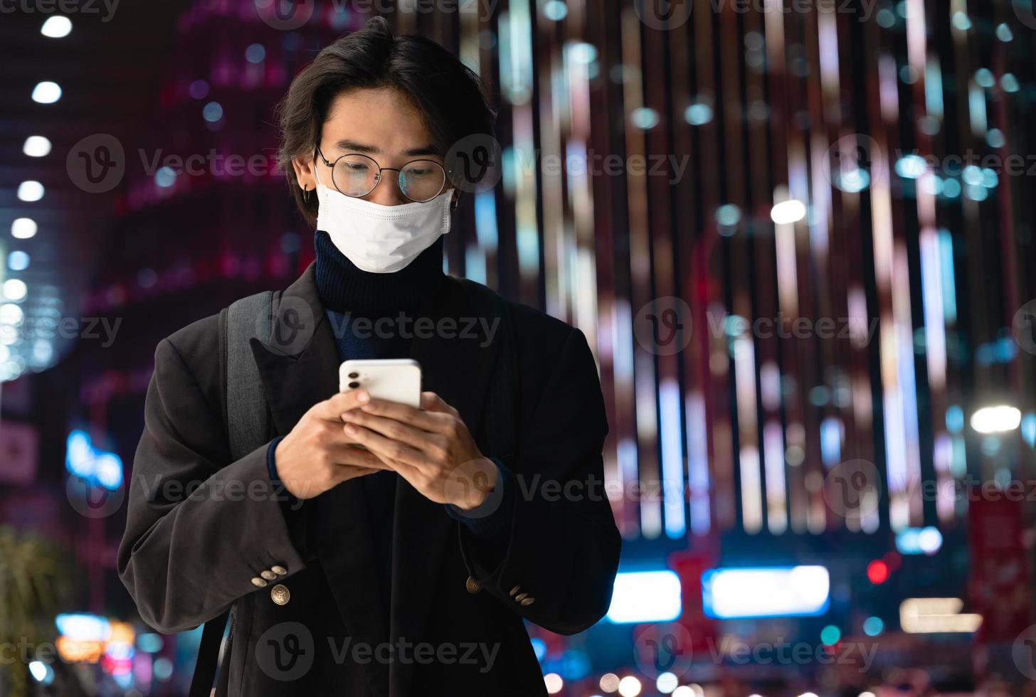 Portrait of an Asian businessman wearing a mask, in the street at night photo