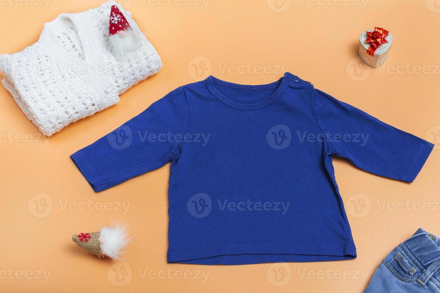 Blue kids raglan, polo shirt and knitted white jacket on colored background, top view close up, mock up with copy space photo