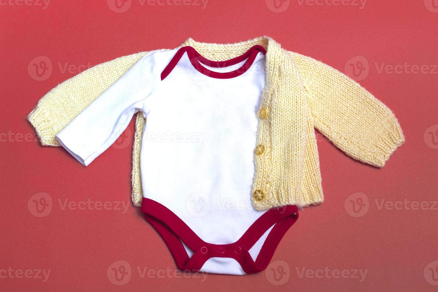 Christmas white baby bodysuit mockup on colored background close up, with knitted yellow jacket, mockup of newborn clothes. With copy space photo