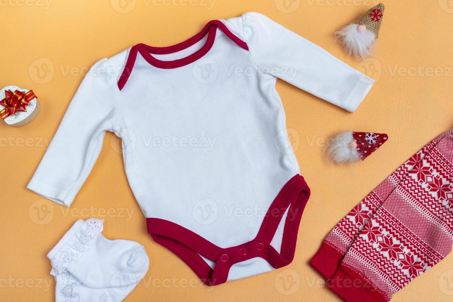 maqueta de un body de bebé blanco sobre un fondo de color de cerca con pantalones rojos y gnomos maqueta de ropa para recién nacidos. con espacio de copia foto