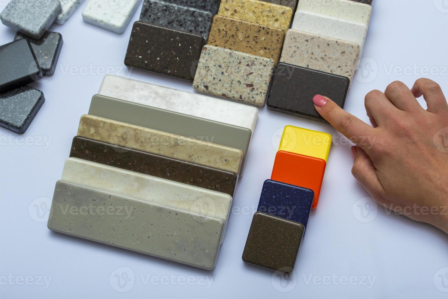 Layout of natural stones top view, close-up. Woman's hand advertises repair material. Floor tiles, tiles, countertops. photo