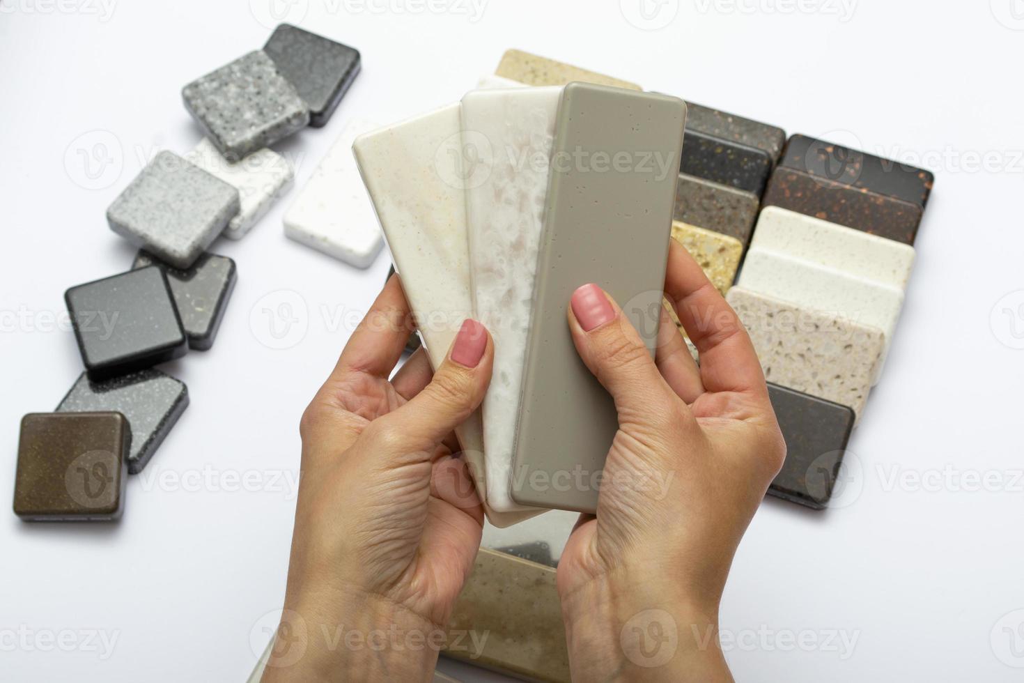 maqueta de piedras naturales, vista superior, primer plano. manos femeninas anuncia materiales de reparación. piso de gres, gres, mesada. foto