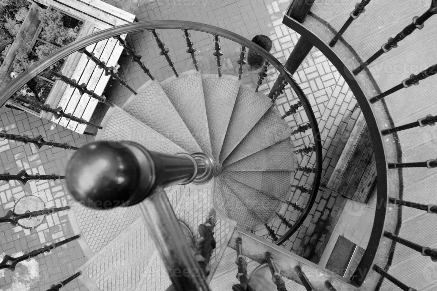 Escalera circular geométrica en el antiguo edificio vista hacia abajo en monocromo foto