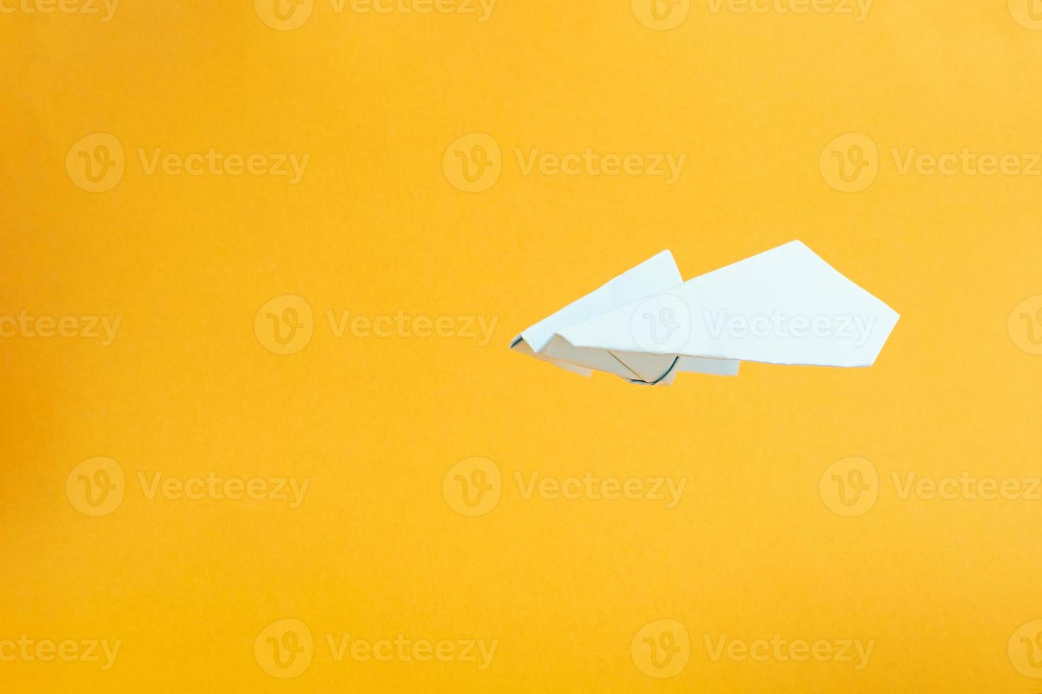 white paper airplane flies on yellow background concept flights and travel photo