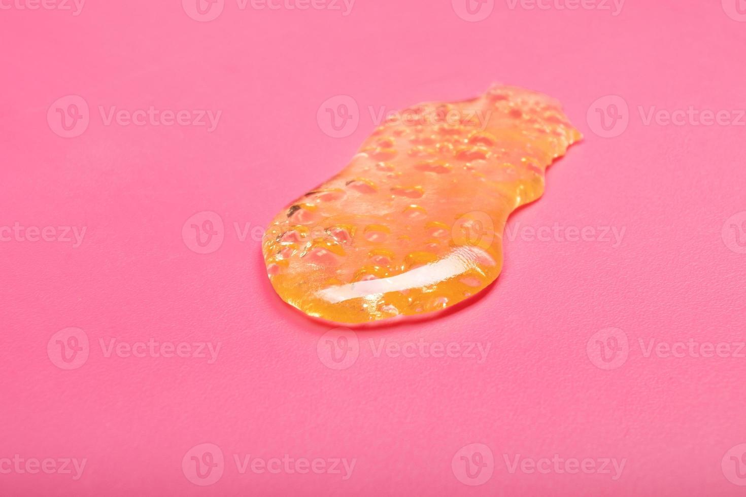 high thc, yellow cannabis wax resin marijuana concentrate on pink background macro photo