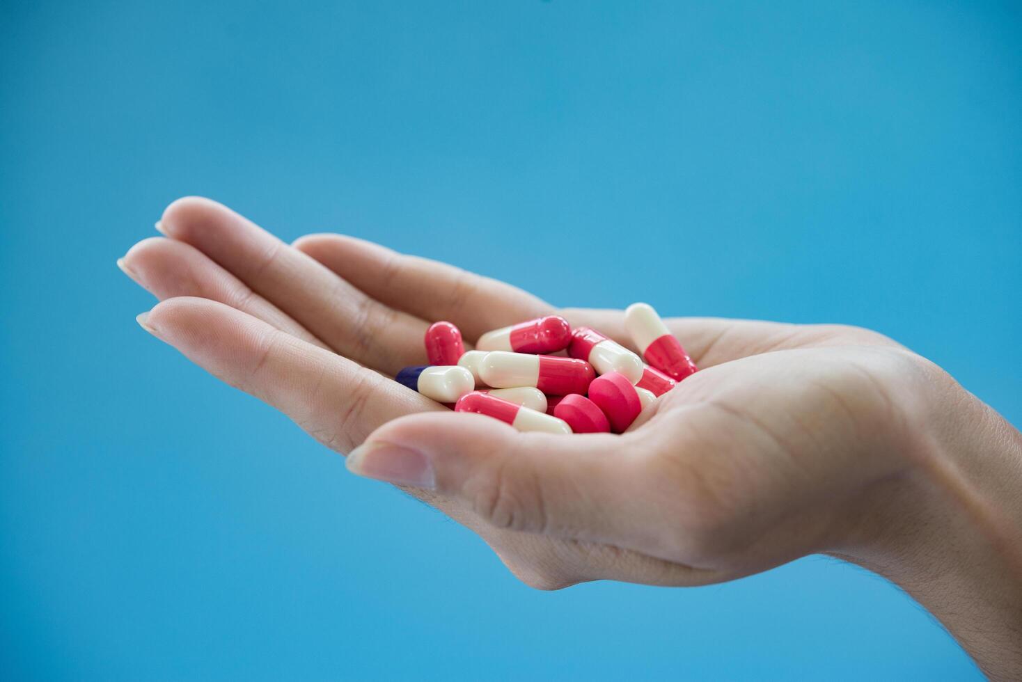 La mano de la mujer vierte las píldoras medicinales de la botella. foto