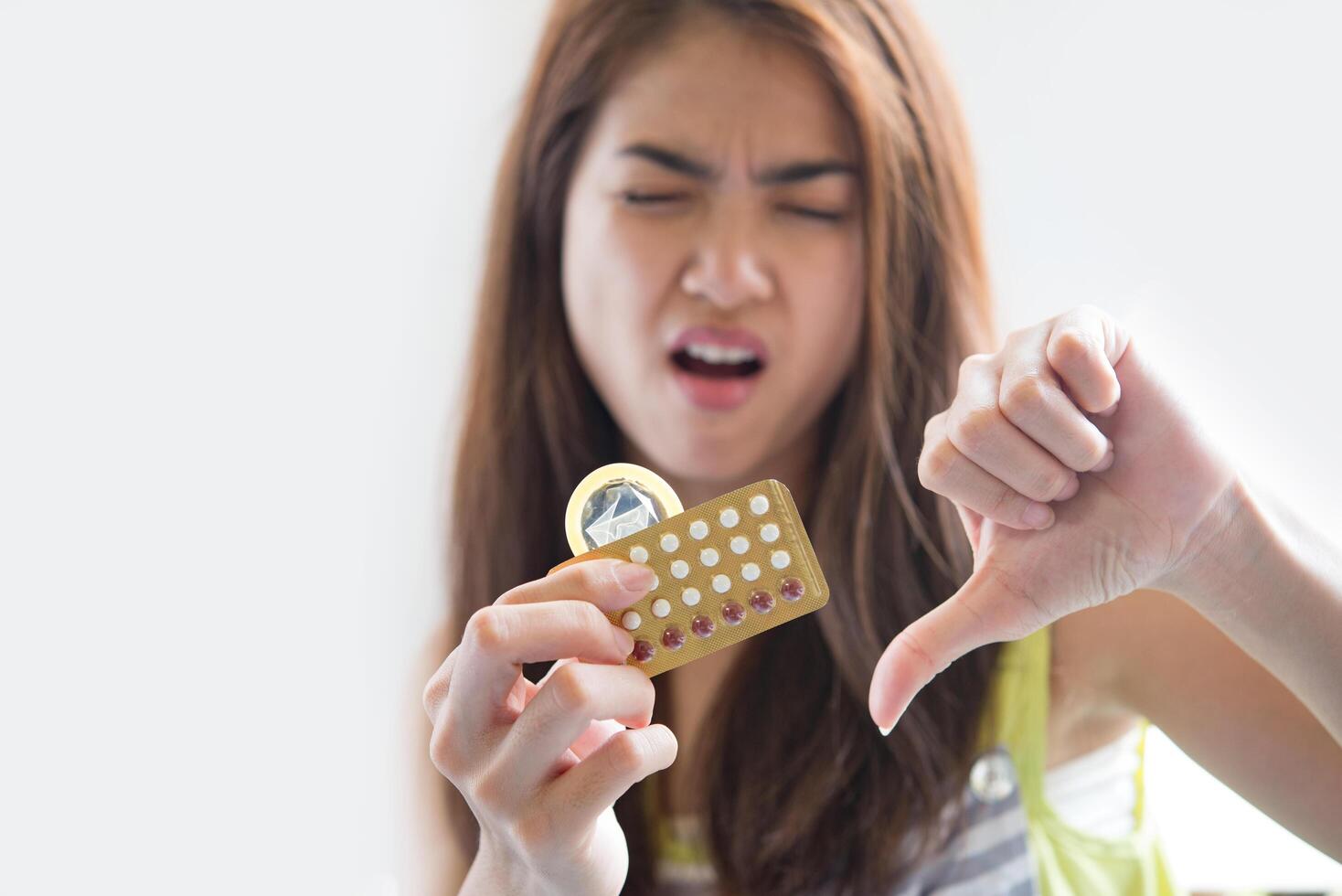 Young woman holding condom and contraceptive pills prevent pregnancy photo