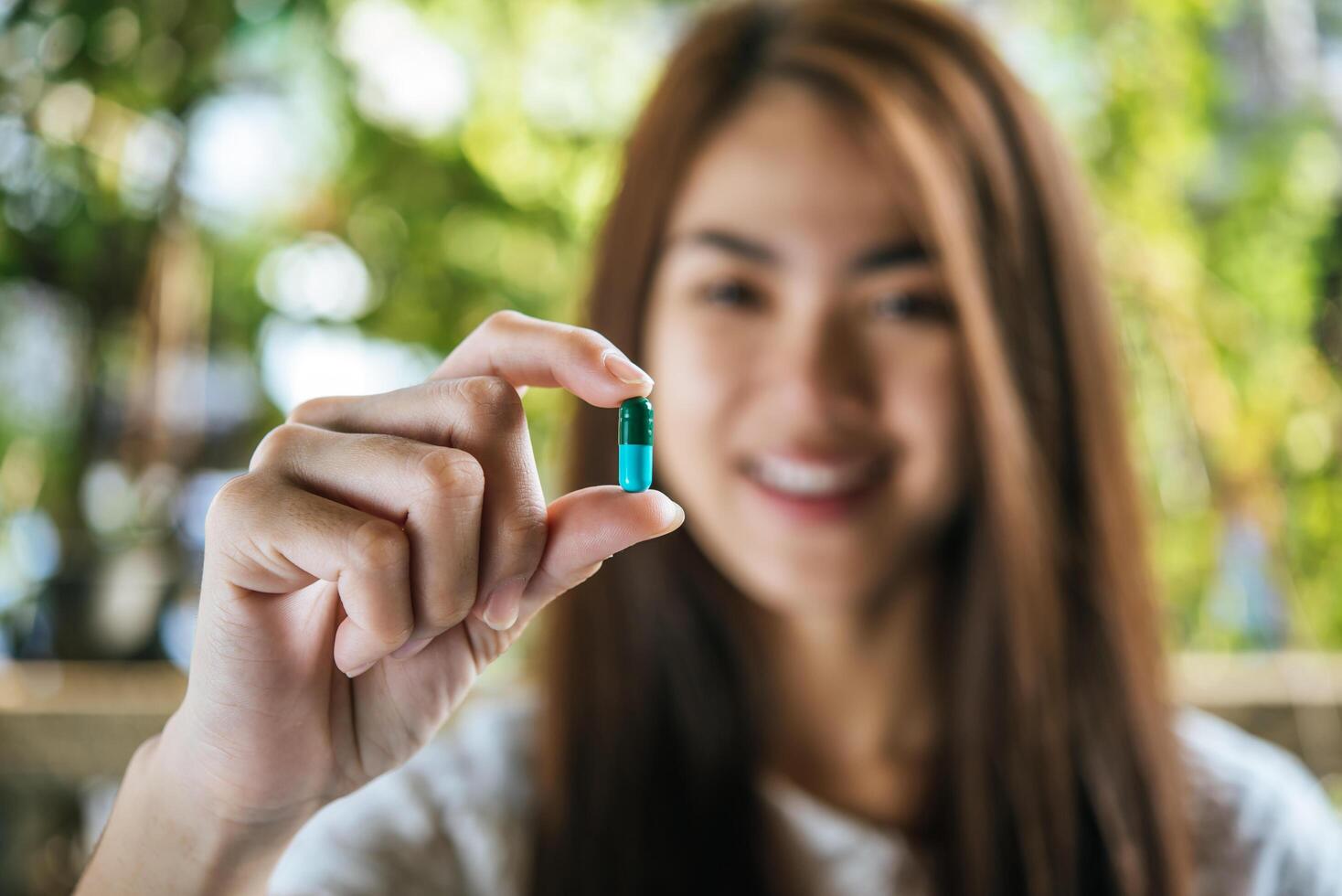 mano de mujer sosteniendo una píldora tomar la medicina de acuerdo con la orden del médico foto