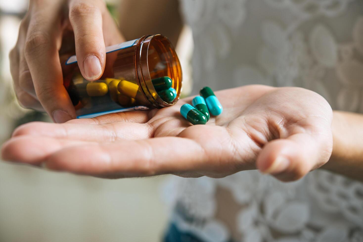 La mano de la mujer vierte las píldoras medicinales de la botella. foto