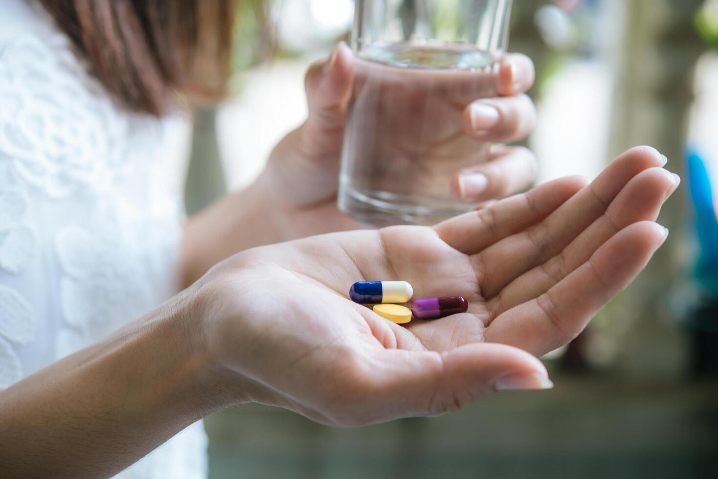 La mano de la mujer vierte las píldoras medicinales de la botella. foto