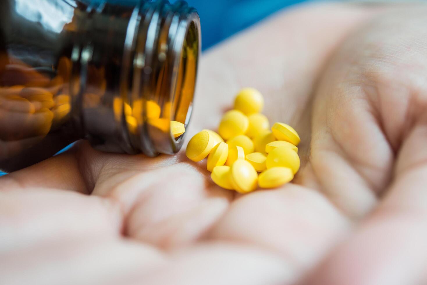 La mano de la mujer vierte las píldoras medicinales de la botella. foto