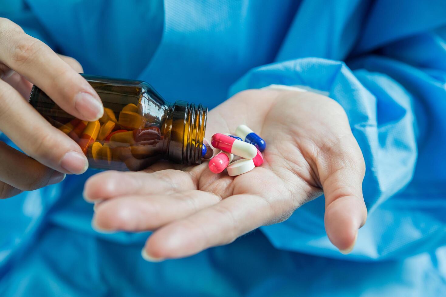 Woman's hand pours the medicine pills out of the bottle photo