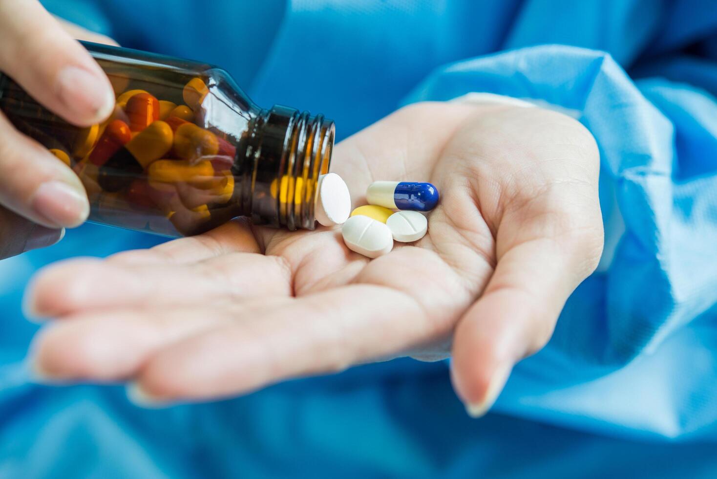 Woman's hand pours the medicine pills out of the bottle photo