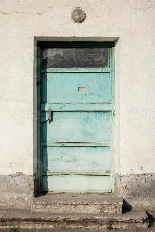 Ugly building with a turquoise color iron door. Aqua blue metal door. photo