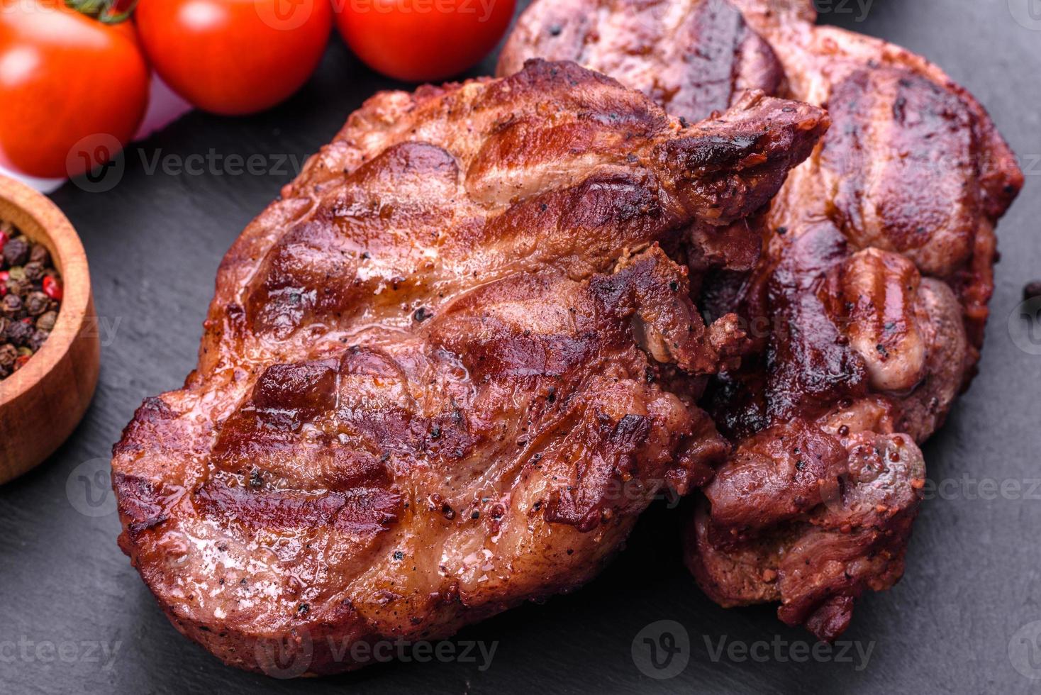 grilled beef steaks with spices on a dark cutting board photo