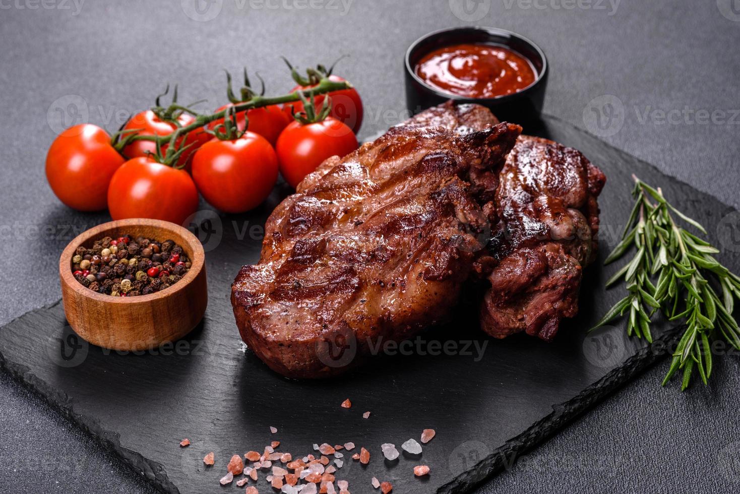 Filetes de ternera a la parrilla con especias sobre una tabla de cortar oscura foto