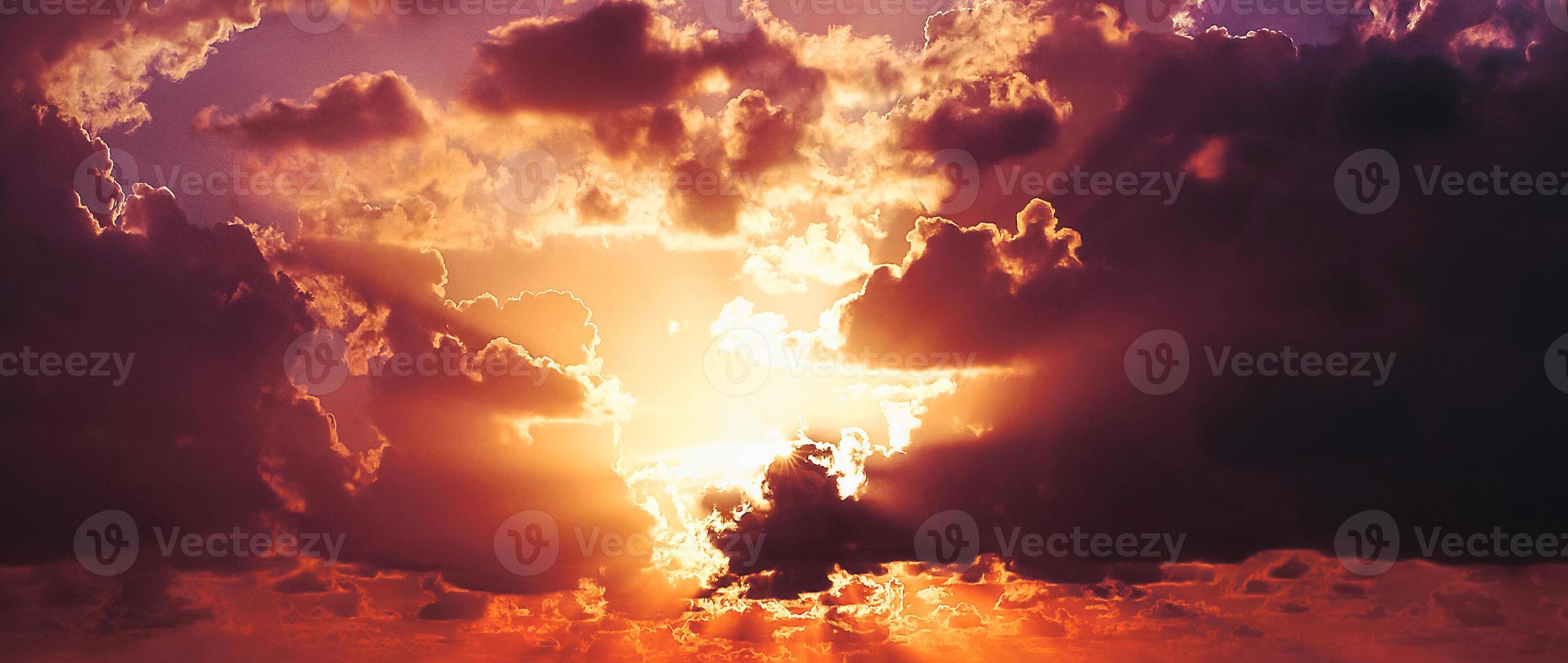 nubes naranjas y grises hermoso ambiente al atardecer con un gran sol amarillo y naranja en las colinas de la superficie del cielo. foto