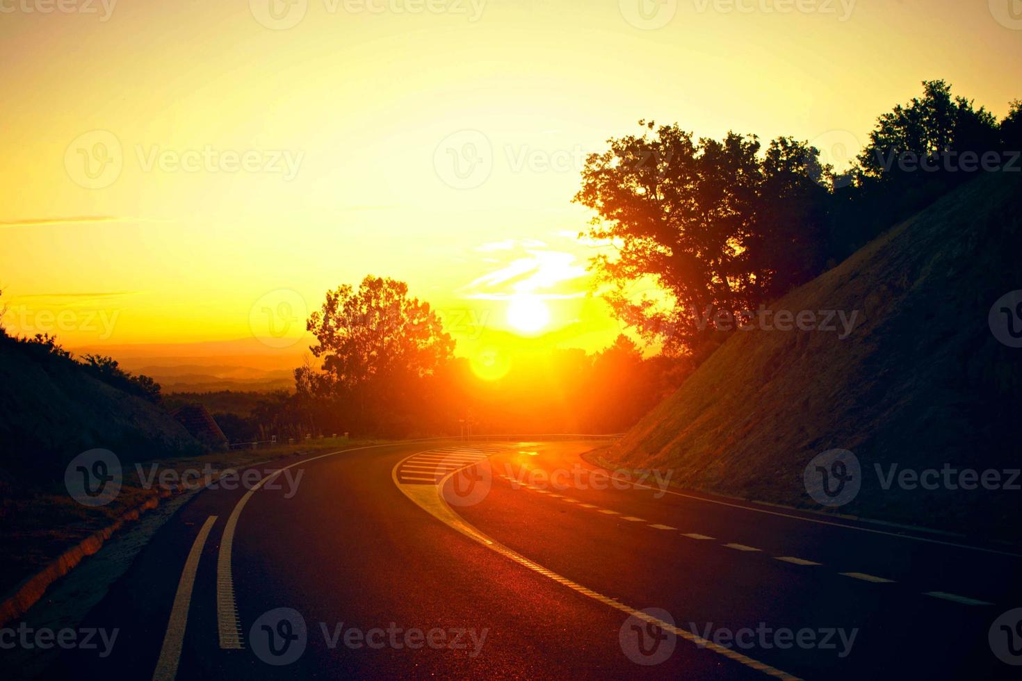 puesta de sol naranja en la carretera pista hermosa carretera girando en las colinas y carretera de montaña carretera de pastizales en la noche en. foto