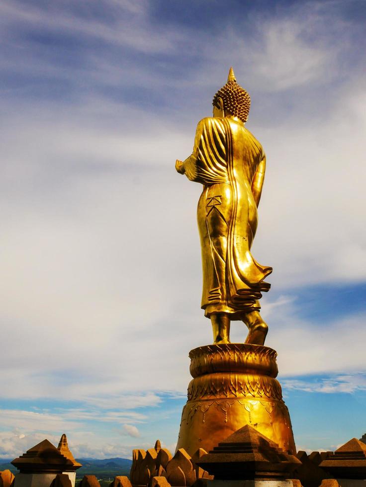 Golden buddha statue on blue sky background belief of buddhism photo