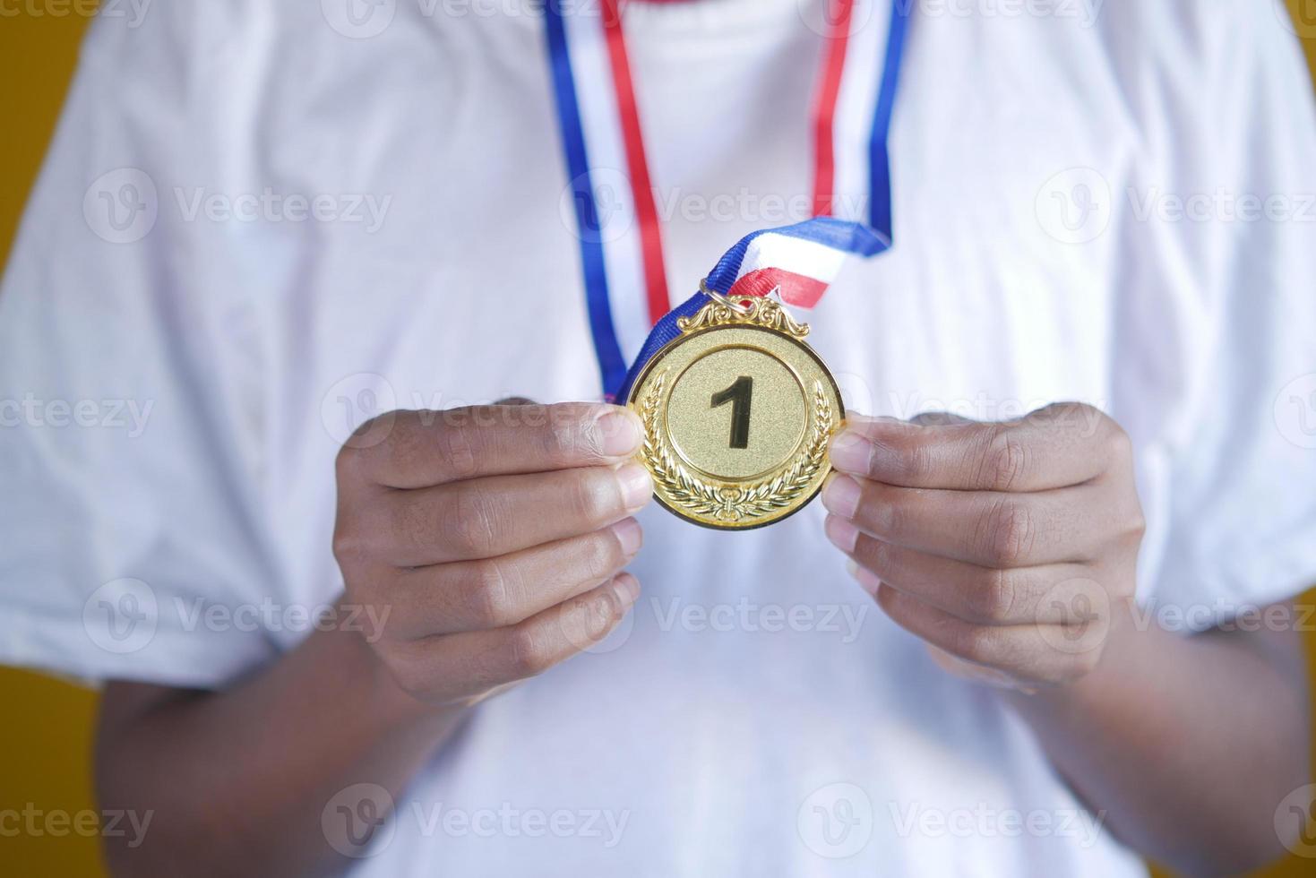 Asimiento de la mano trofeo del primer lugar contra el fondo amarillo foto