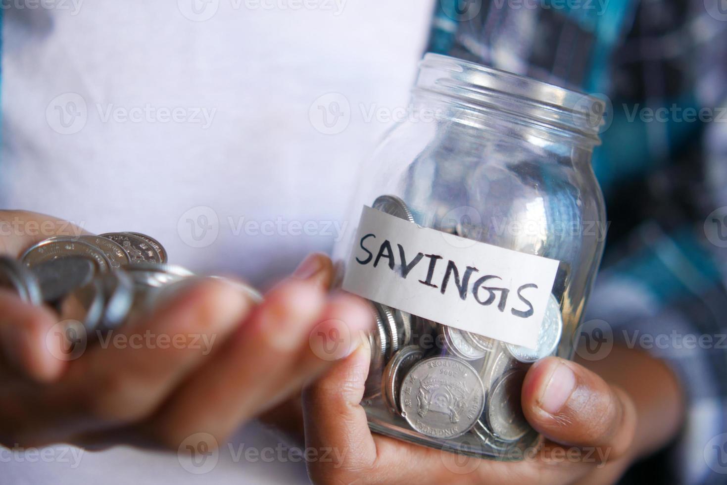 young man hand hold saving coins jar photo