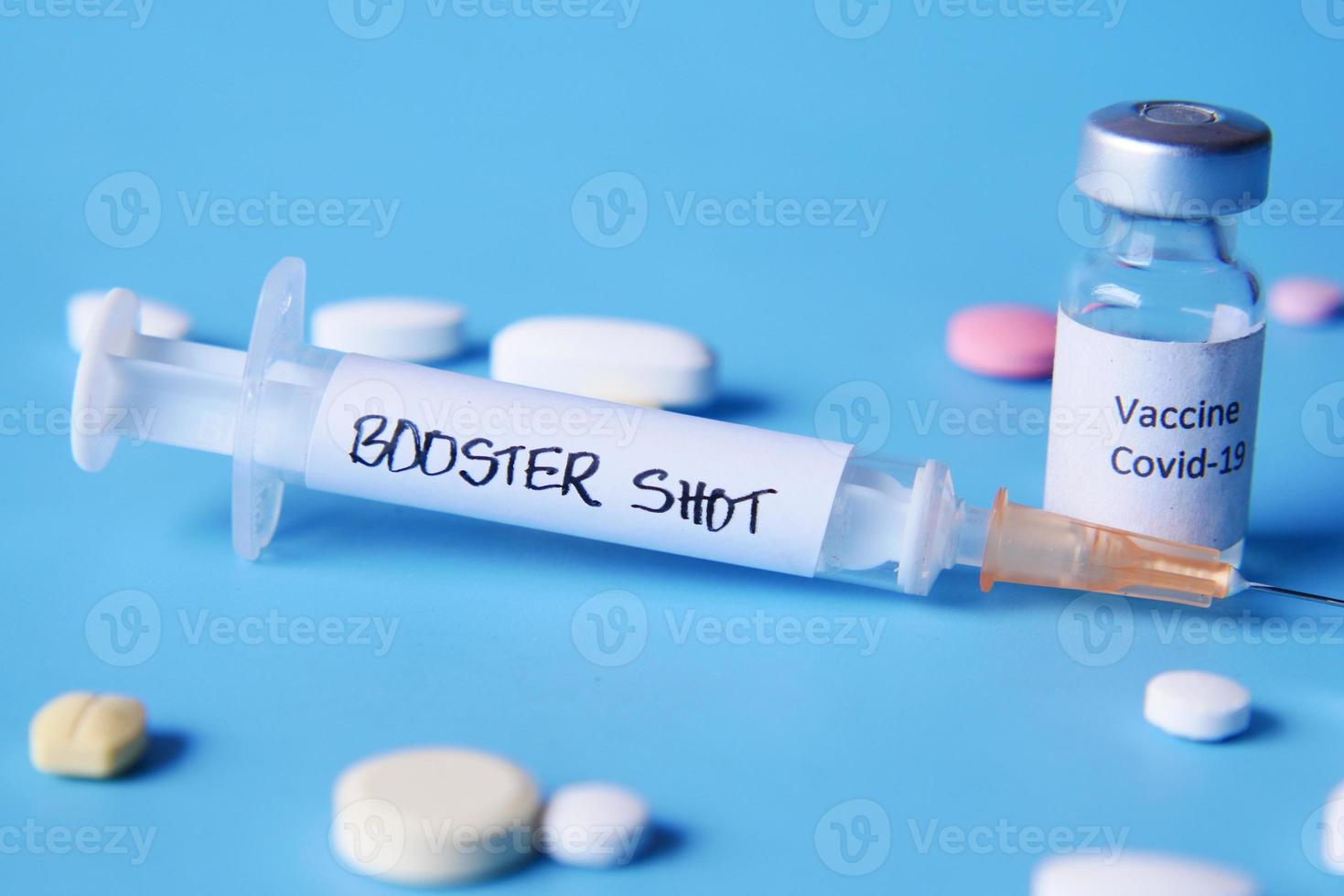 booster shot dose coronavirus vaccine and syringe on blue photo