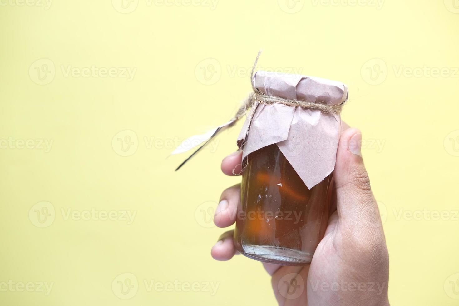 hand hold fresh honey in a glass jar photo