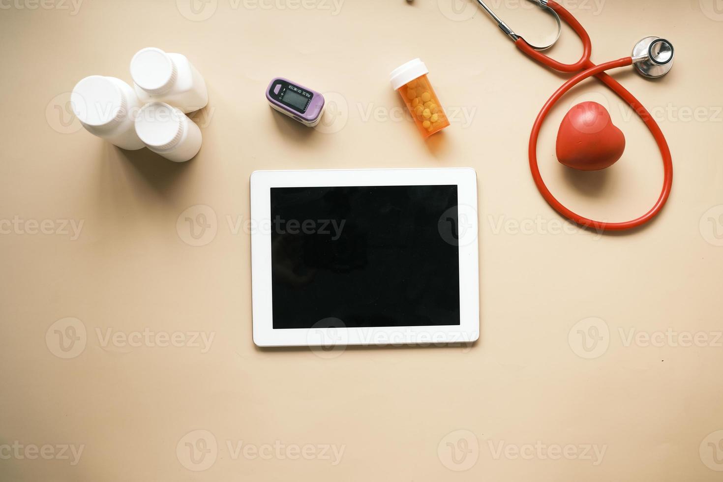 digital tablet, stethoscope and pill container on table photo