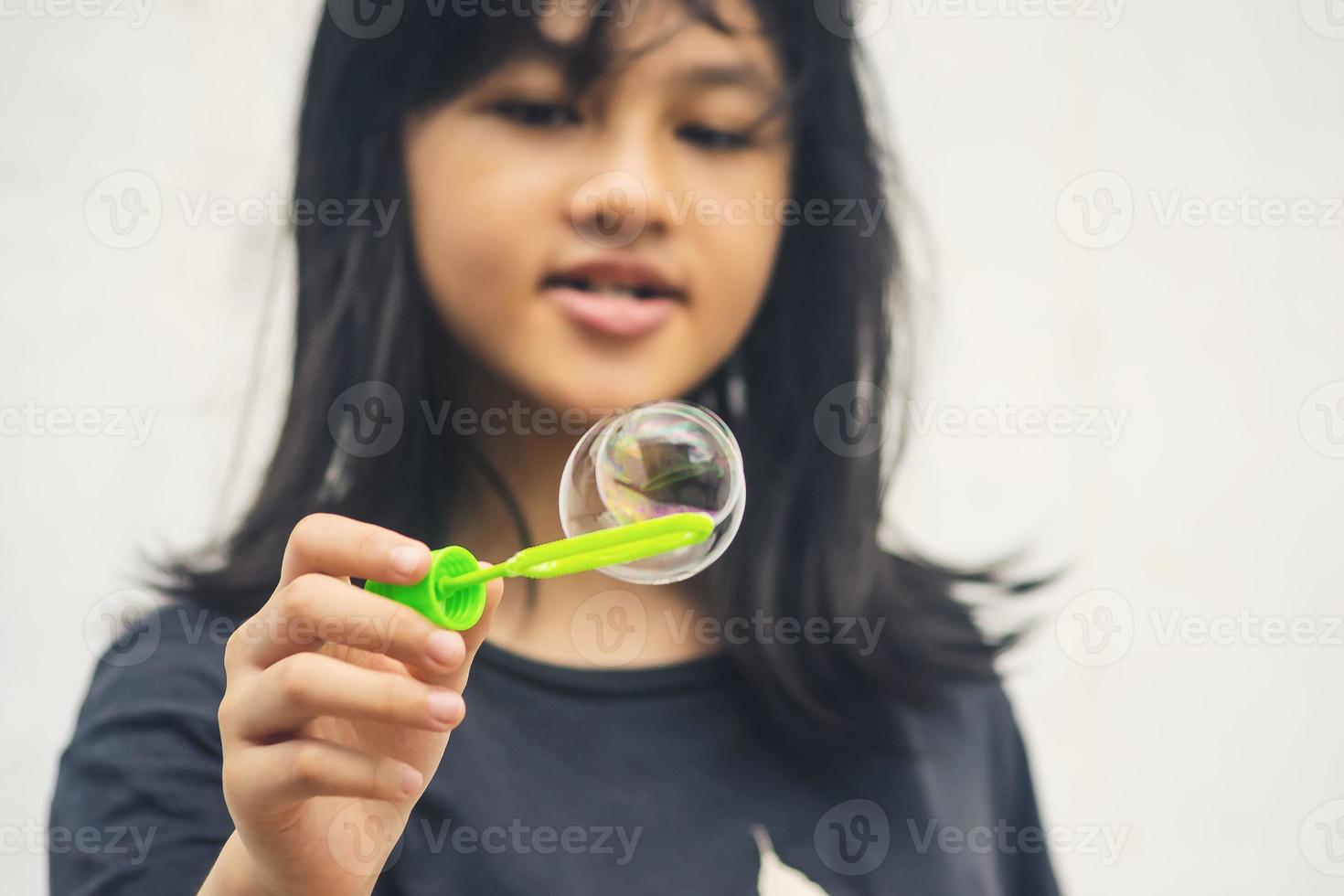 A girl holding a bubble maker and blowing them out. photo