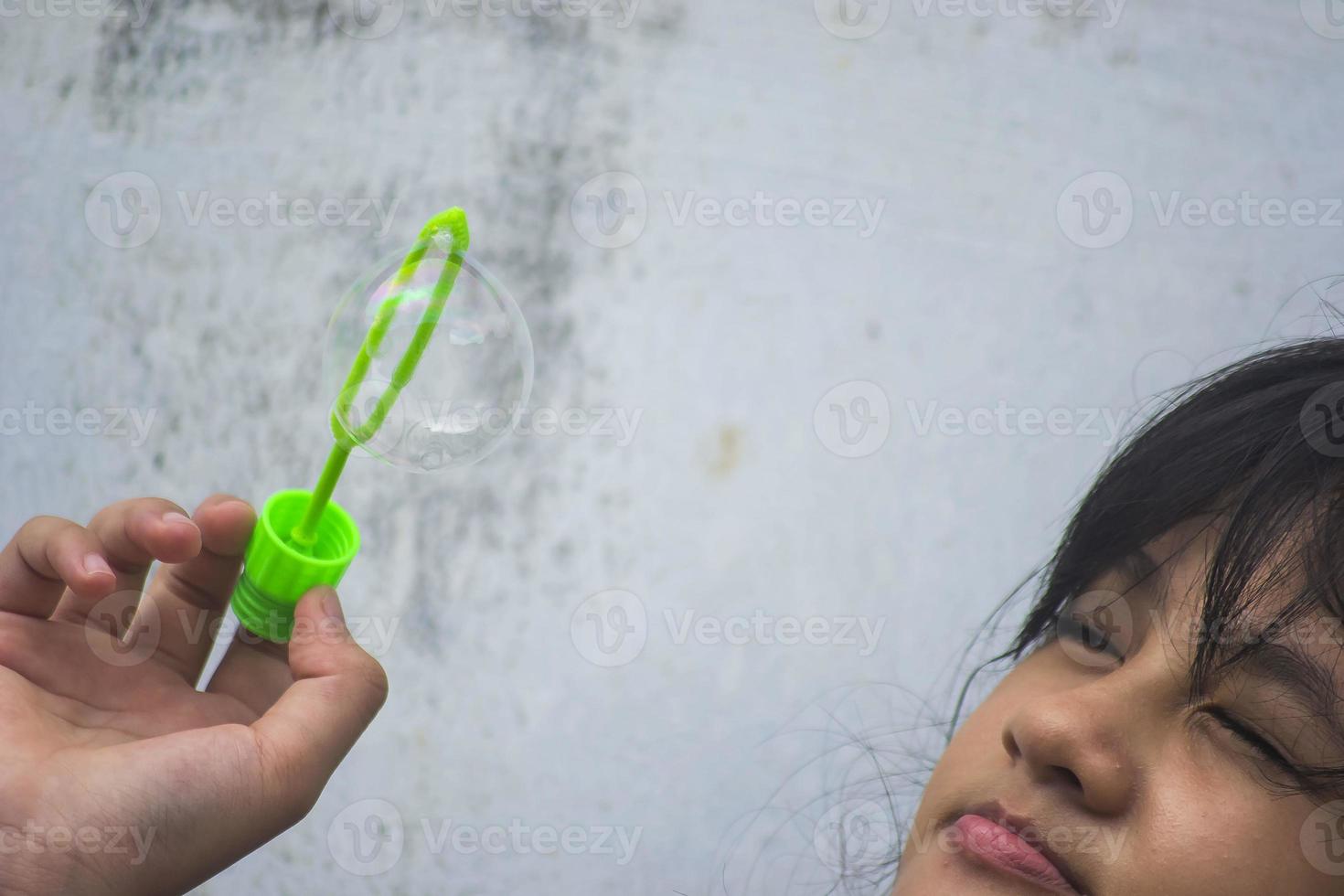 A girl holding a bubble maker and blowing them out. photo
