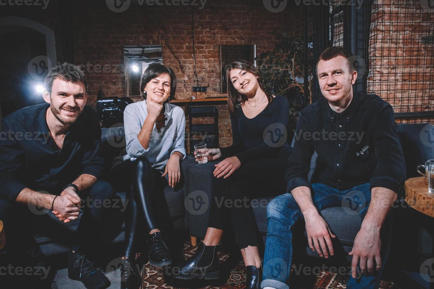 Cheerful guys and girls are sitting on sofa photo