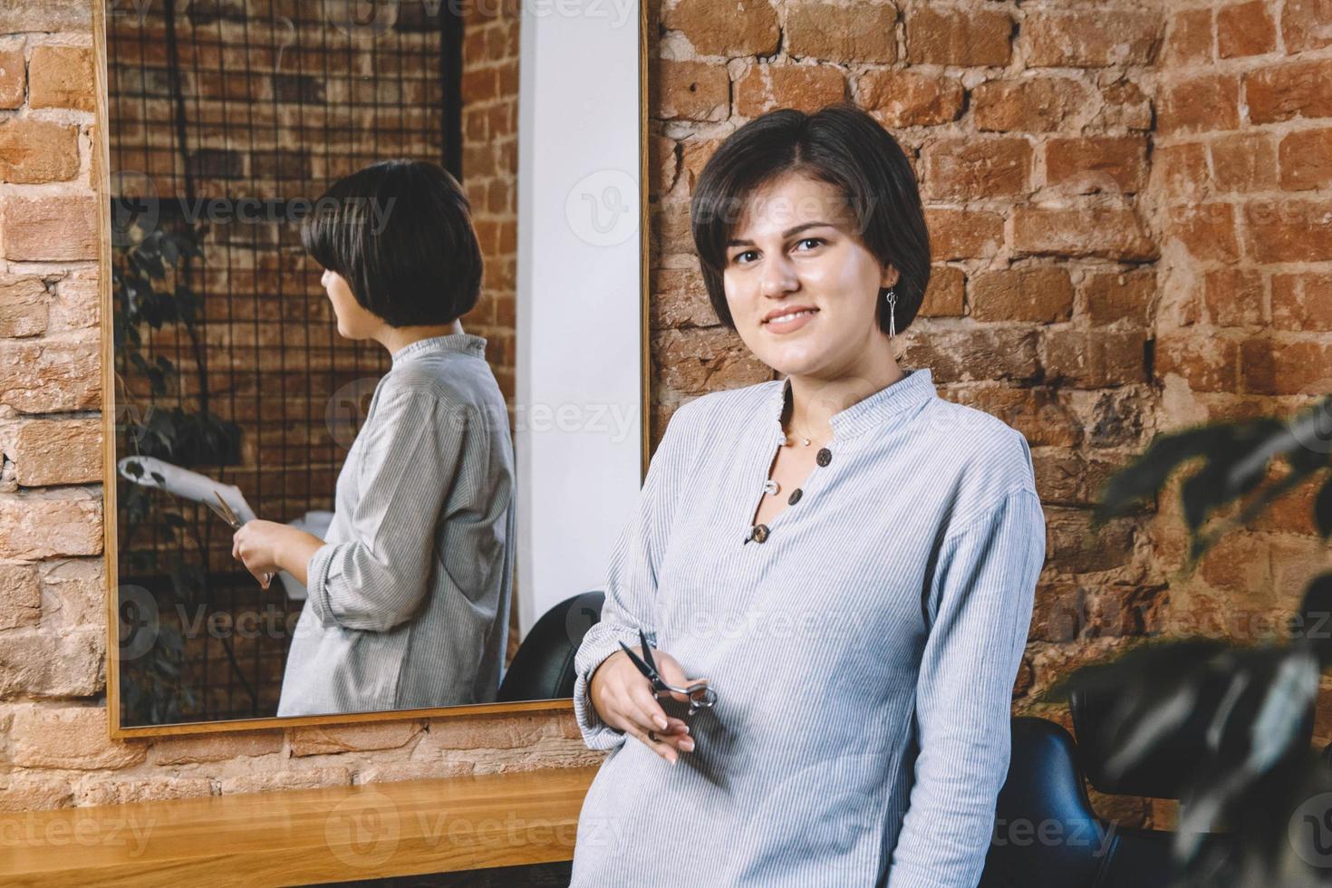 Young beautiful hairdresser woman with scissors in hand in the barbashop salon photo