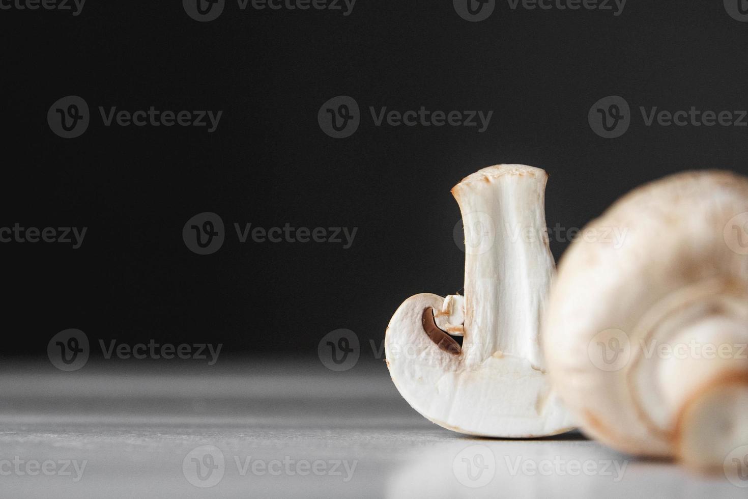 Mushrooms champignons lie in a row on a white table on a dark background photo