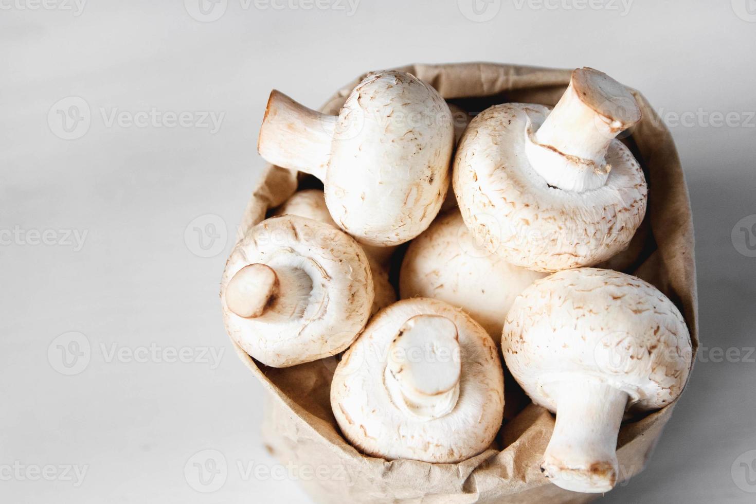 Champiñones champiñones en una bolsa de papel sobre una mesa de madera blanca foto