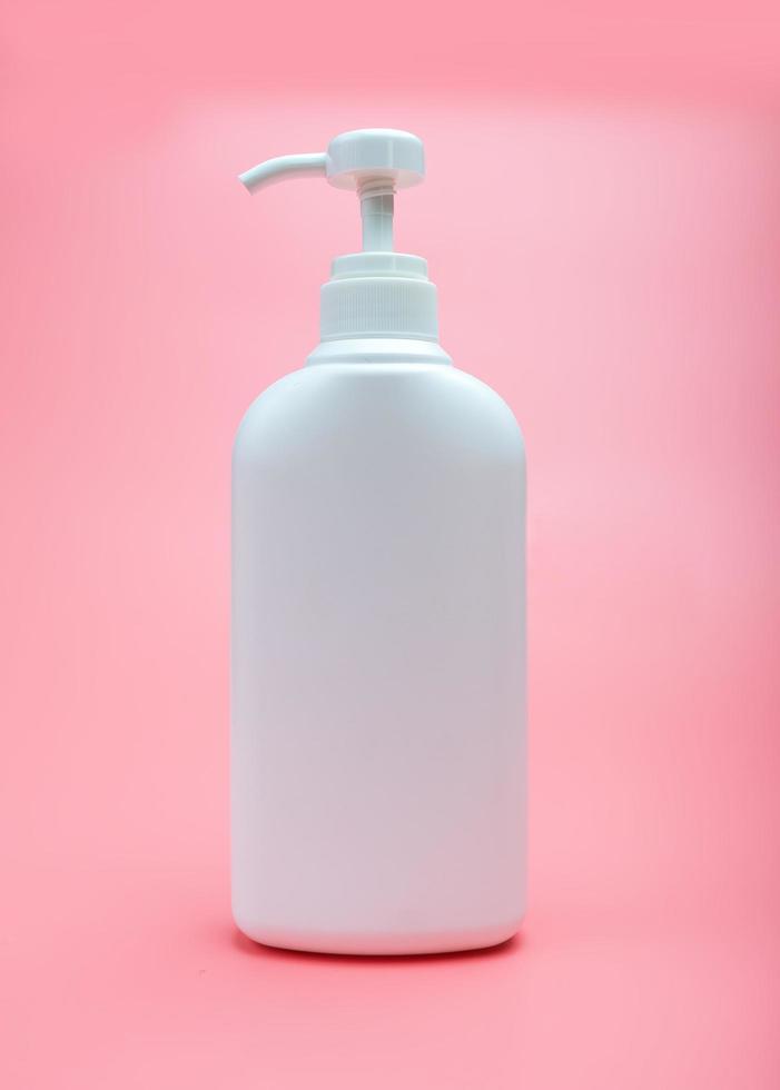 Botella de bomba de plástico blanco para cosméticos para el cuidado de la piel sobre fondo rosa foto